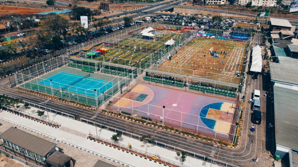 Aerial shot of colorful sports complex with tennis, basketball courts, and running tracks.