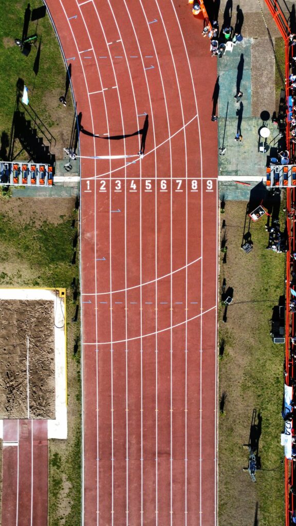 pexels-photo-18588227-18588227 Aerial view capturing a vibrant track and field stadium with a focus on the finish line and lanes.
